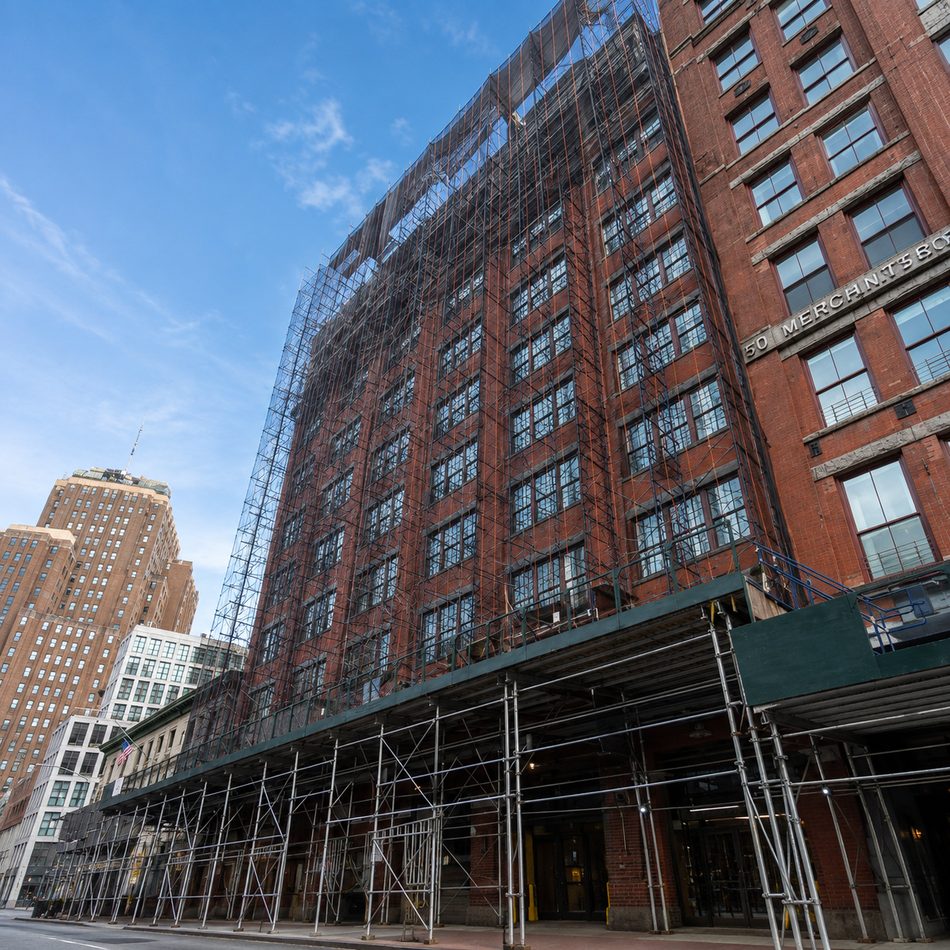 Scaffolding and sidewalk protection wrapping a brick building during a LINE Construction Group restoration